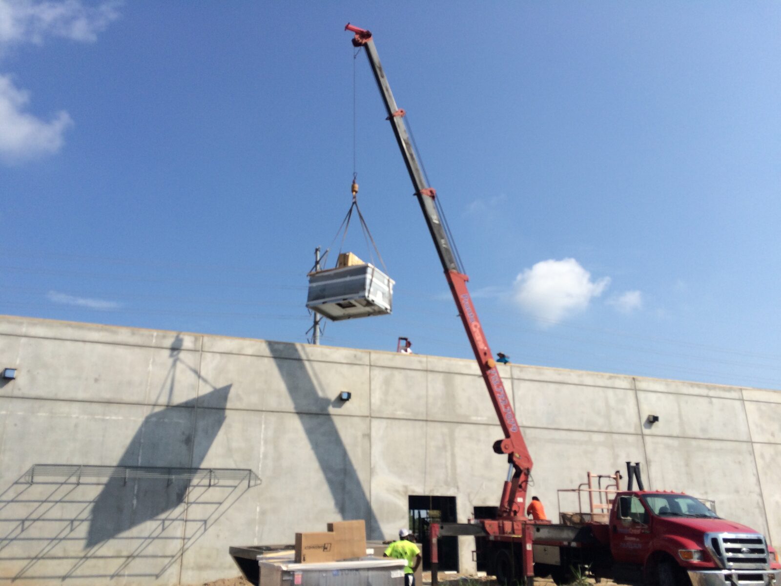 A crane lowering a unit behind a tilt-wall building