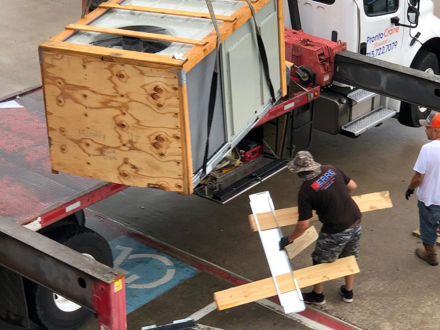 Ferre crew unloading a crated rooftop unit from a truck