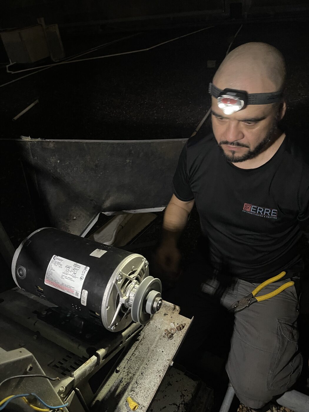 A Ferre technician working inside equipment by headlamp