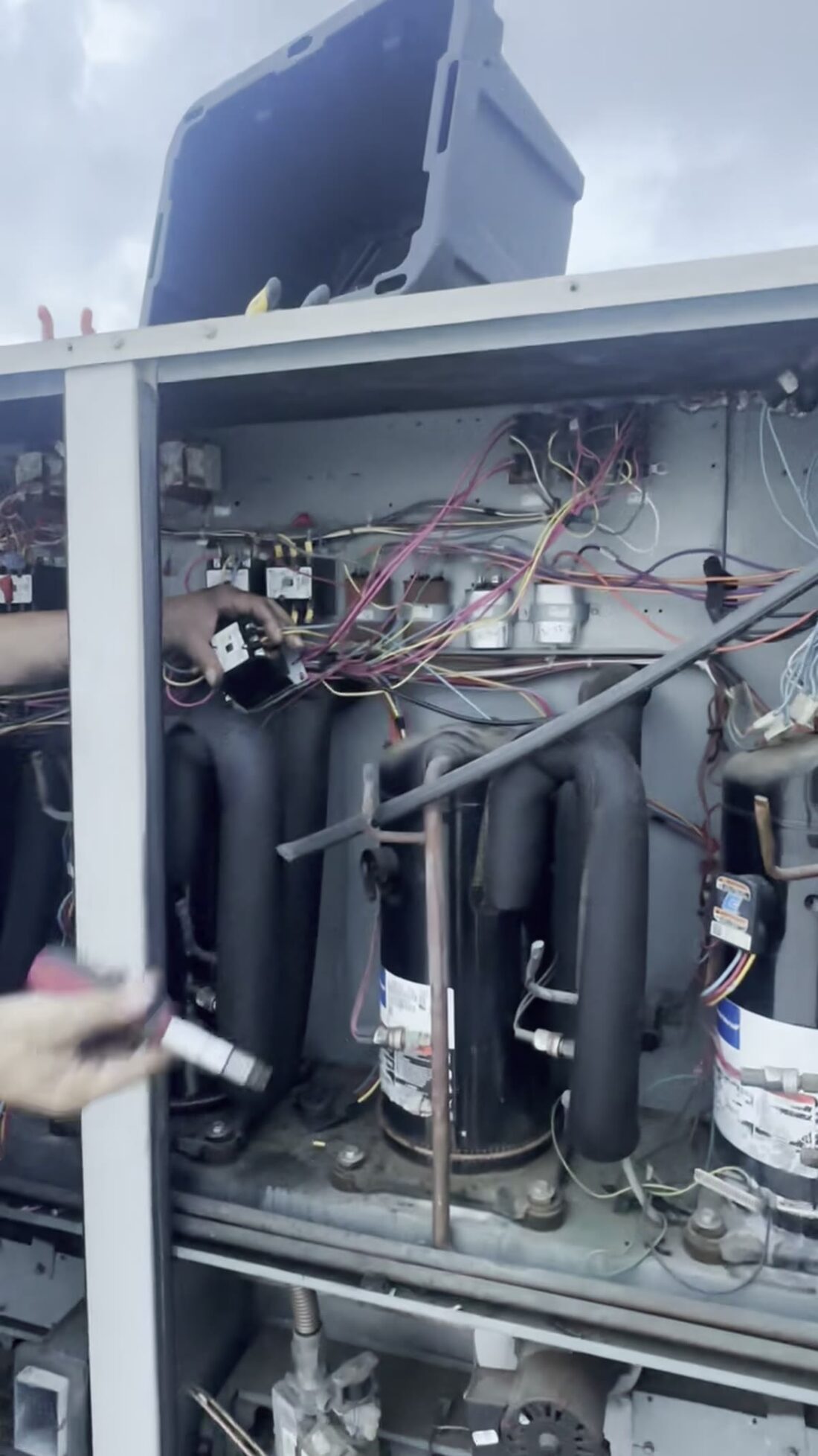 Hands in the compressor bay, panel open.