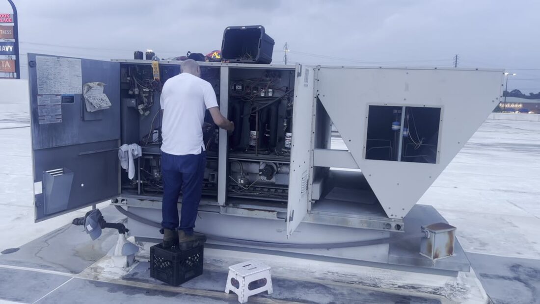 Standing on a crate to reach the top of a big packaged unit.