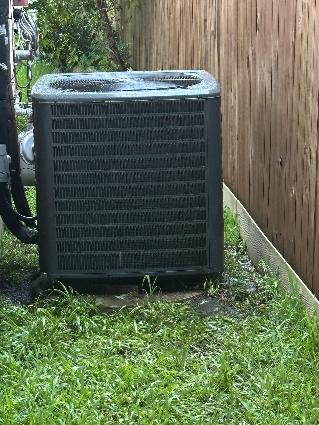 A residential condensing unit standing in a back yard