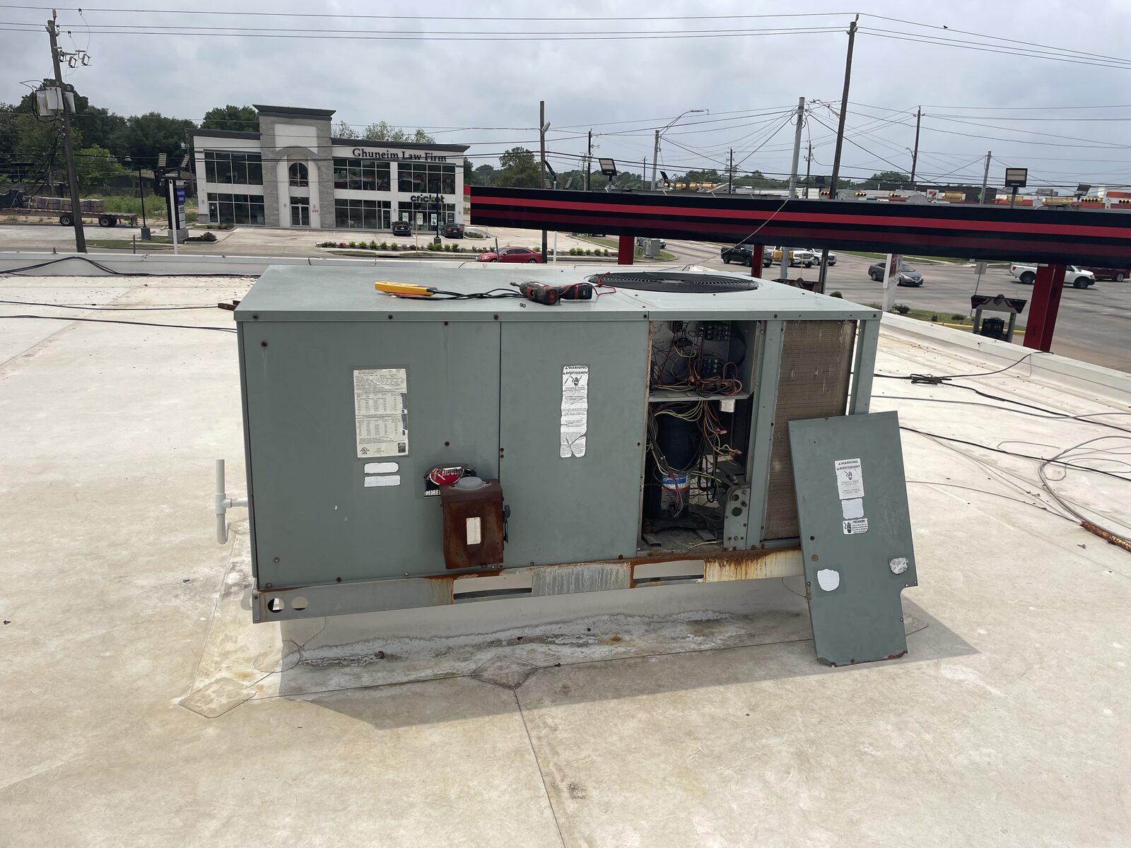 A commercial rooftop unit with its service panel open on a Houston roof